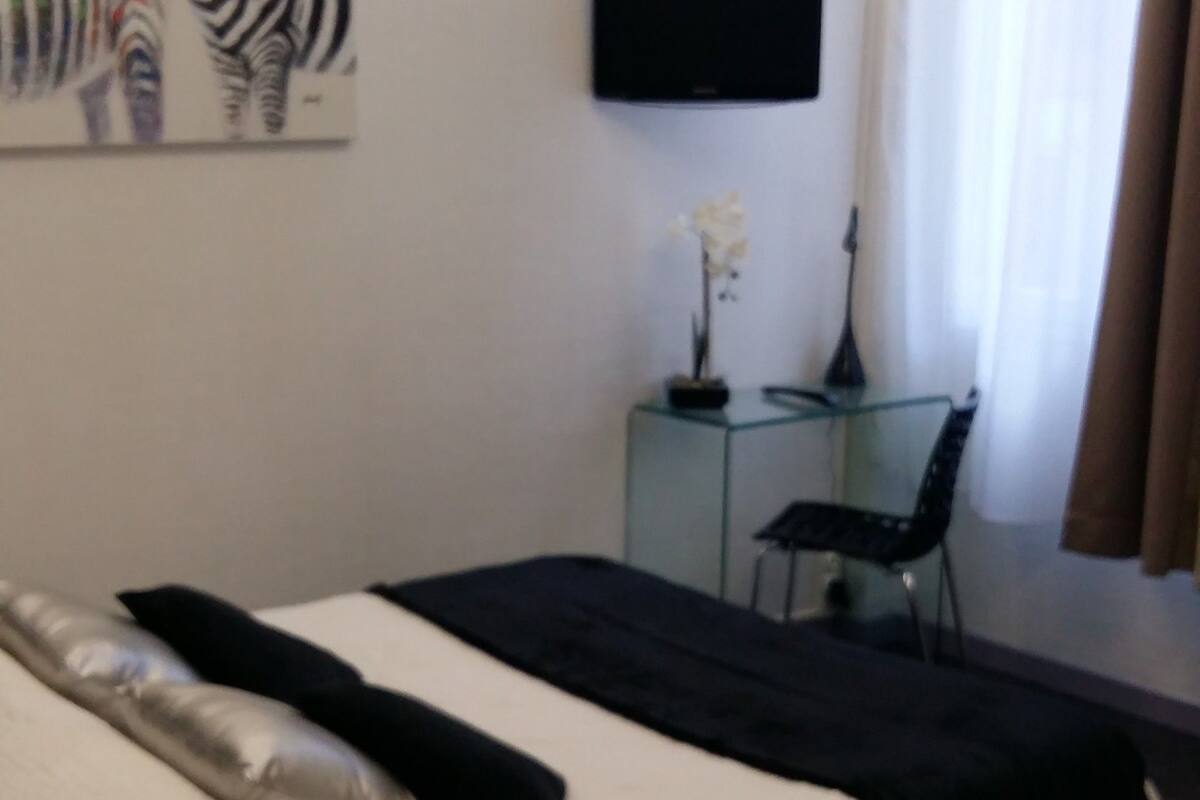 Ein Hotelzimmer mit Bett, Schreibtisch, Stuhl, Fernseher und einem Zebra-Bild an der Wand.
