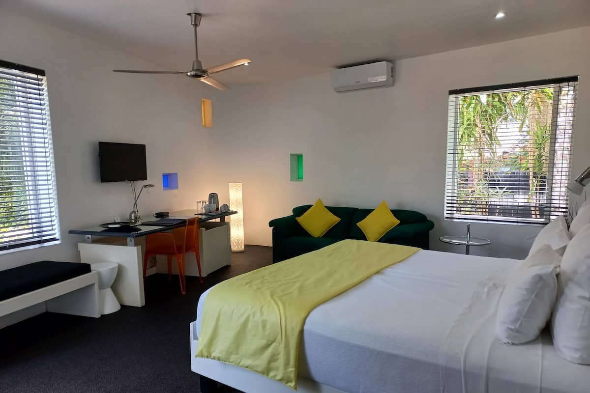 Een hotelkamer met een bed, bureau, stoel en plafondventilator.
