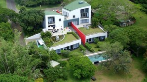 Een modern huis met twee verdiepingen, een ruime voortuin, een zwembad en een overdekt terras.