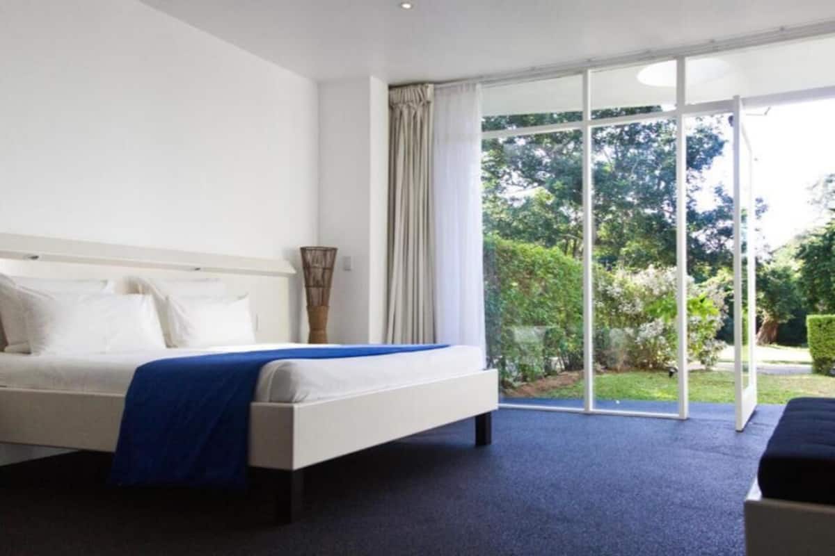 Een slaapkamer met een bed, een raam en uitzicht op groen.