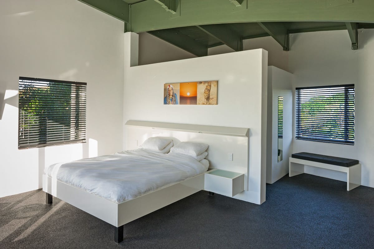 Een moderne slaapkamer met een bed, nachtkastjes en een bankje.