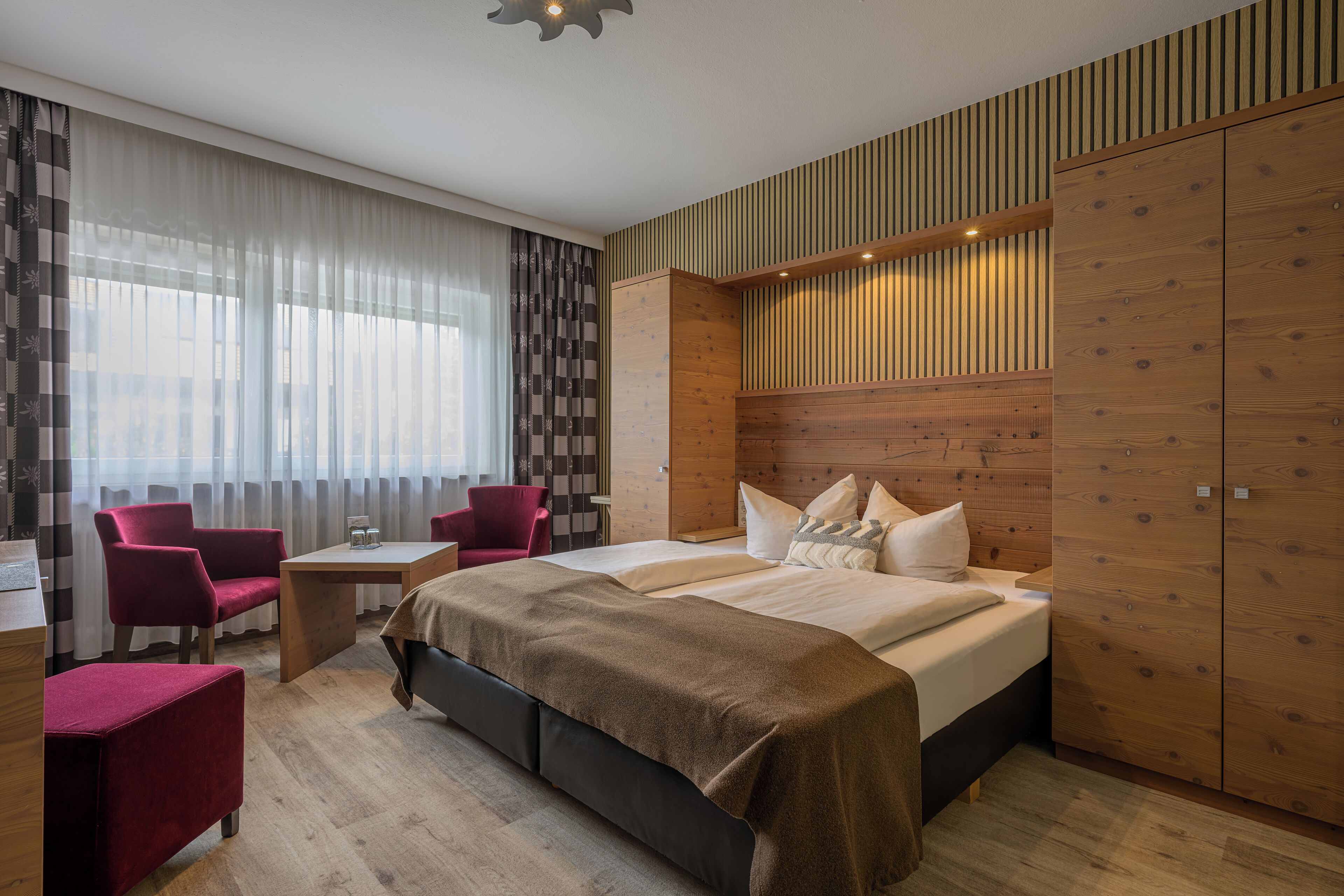 Una habitación de hotel moderna con una cama grande, un escritorio, una silla y un armario.
