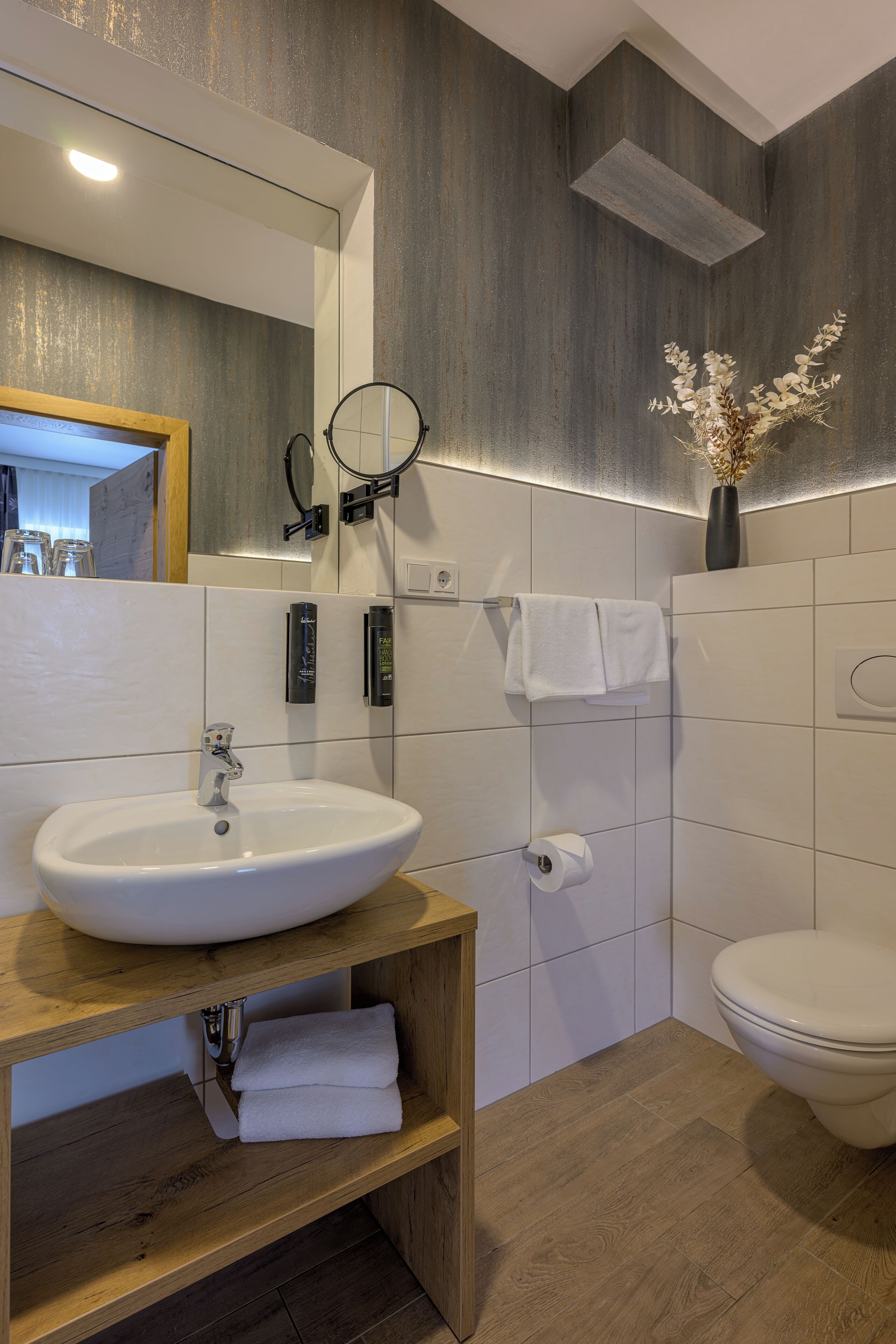 Ein modernes Badezimmer mit einem weißen Waschbecken, einer Holzausstattung und einer Toilette.