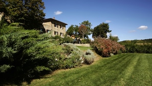 A stone building with a sloped roof, surrounded by well-maintained lawns and various shrubs. - Tenuta Ponziani - Griffin's Resort (Orvieto)