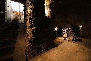 A dimly lit interior with stone walls, a staircase, and a display of bottles. - Tenuta Ponziani - Griffin's Resort (Orvieto)