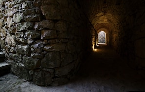 A stone tunnel with a narrow passageway leading to a small window at the end. - Tenuta Ponziani - Griffin's Resort (Orvieto)