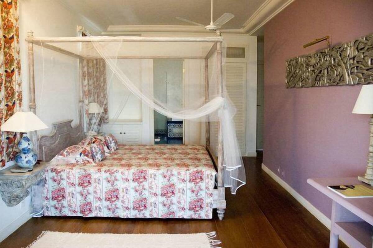 Un dormitorio con cama con dosel, dosel decorativo, un adorno en la pared y una mesita de noche con lámpara.
