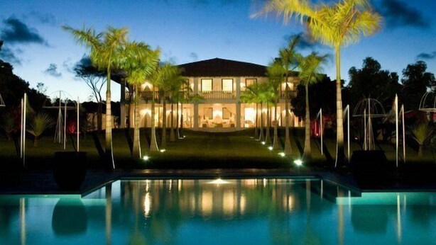 Un grand bâtiment bien éclairé, avec une piscine en premier plan.