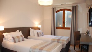 Una camera d'albergo con due letti, una scrivania e una sedia.