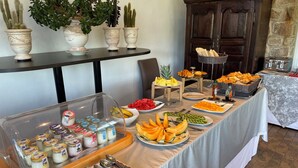 Un tavolo per buffet con diversi cibi, tra cui frutta, pasticcini e condimenti.