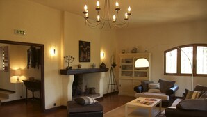 Un soggiorno accogliente con camino, comodi posti a sedere e un lampadario.