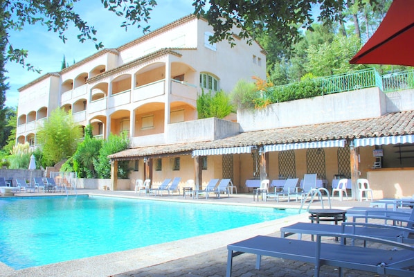 Una piscina al aire libre, sombrillas, tumbonas