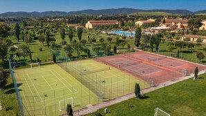 Luchtbeeld van een sportcomplex met meerdere tennisbanen, omgeven door groen en woongebouwen.