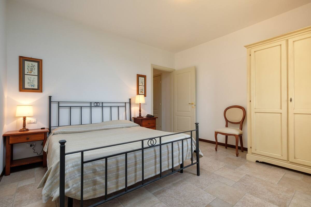 Une chambre à coucher comprenant un lit, des tables de chevet, une armoire et une chaise.