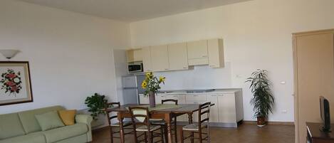 A compact living space with a dining area, kitchenette, and a sofa.