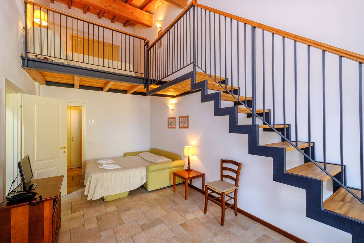 Une chambre à coucher avec un lit, une chaise, un bureau et un escalier.
