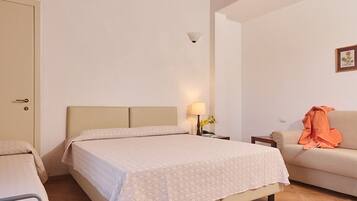 Un dormitorio con cama, sofá, mesita de noche y techo de madera.