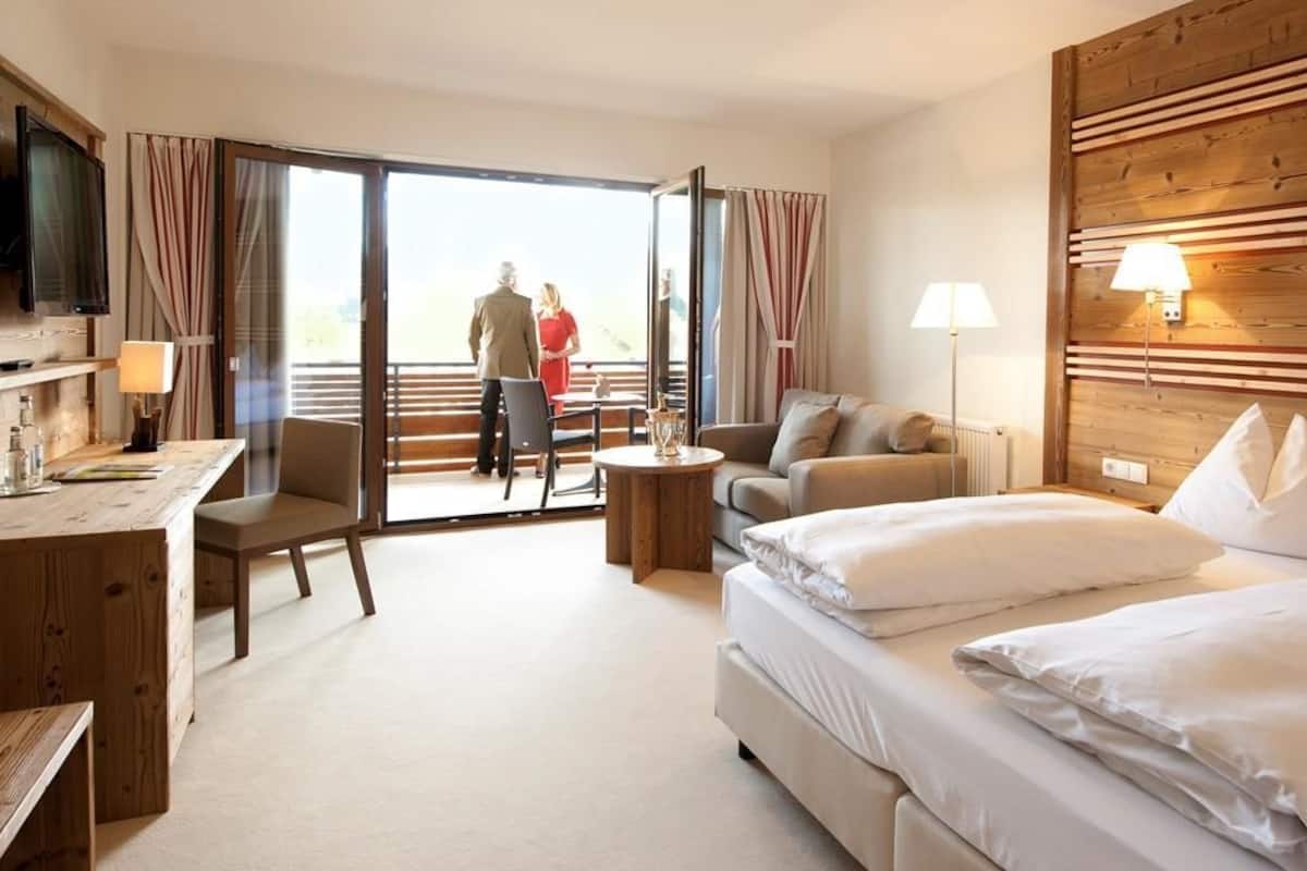 Une chambre d’hôtel avec un lit, un bureau, une chaise, un canapé, une lampe et une vue sur l’extérieur.