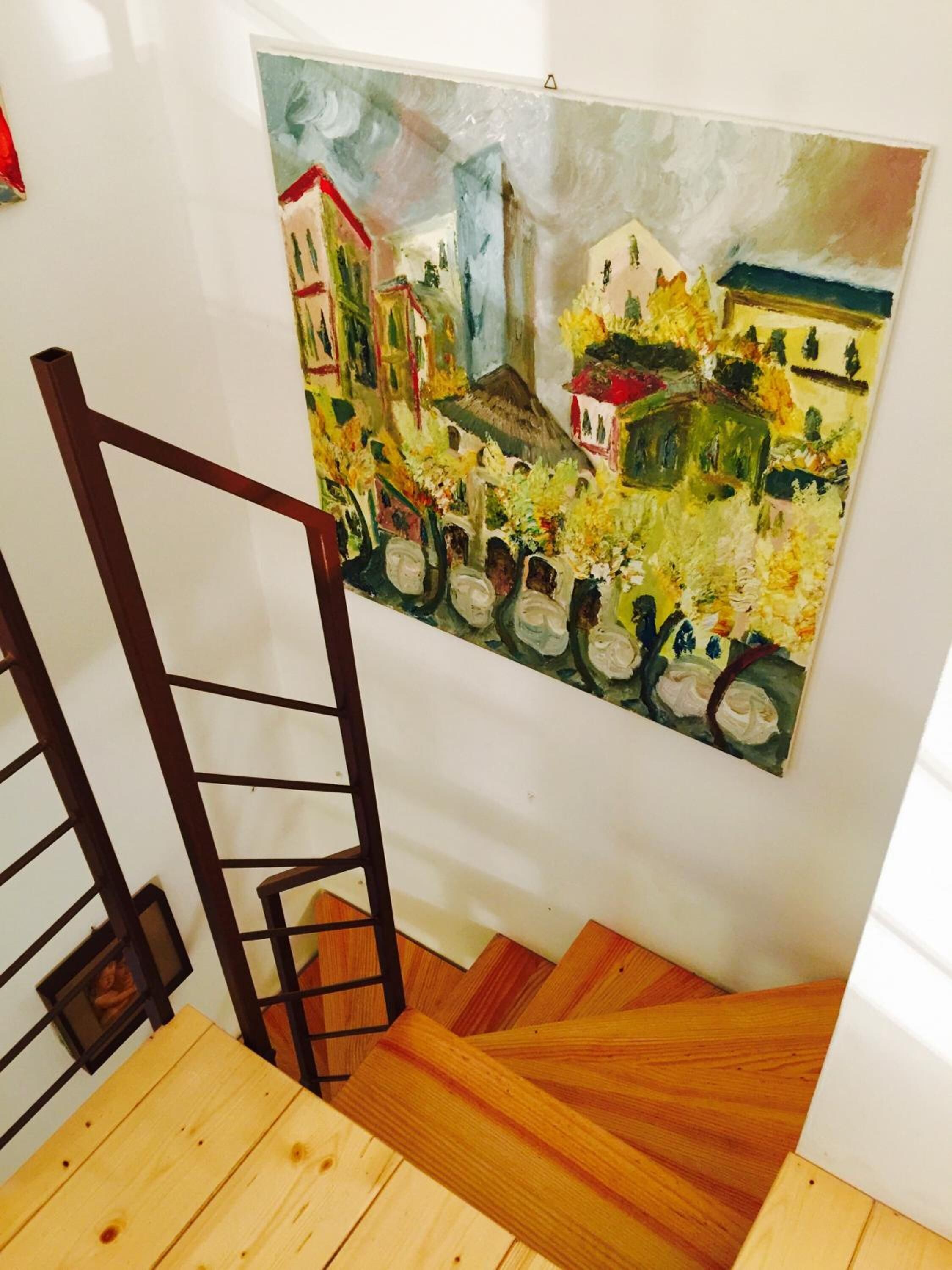 A wooden staircase with a painting of a cityscape on the wall.