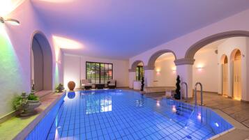 Een binnenzwembad, ligstoelen bij het zwembad