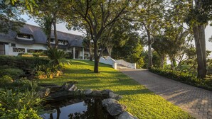 A house with a pond, a pathway, and a well-maintained lawn.