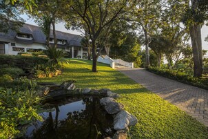 Una casa con un estanque, un camino y un césped bien cuidado.