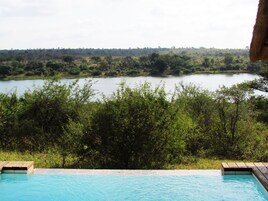 Una piscina con vista a un lago y follaje circundante.
