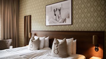 A neatly made bed with a headboard, a framed picture on the wall, and a bedside lamp.