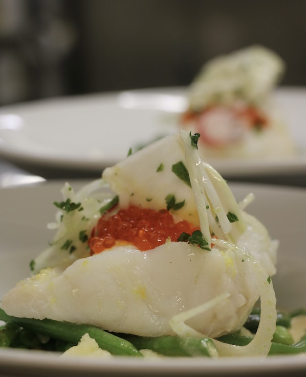 A plate of food with a white fish fillet, green vegetables, and a red sauce. - Åhus Gästgivaregård (Aahus)