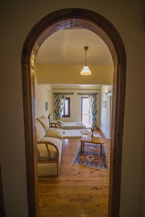 A hallway leading to a room with a sofa, a small table, and a patterned rug.
