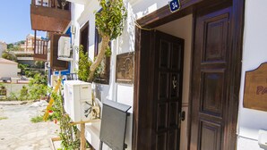 A building with a wooden door, potted plants, and a sign with handwritten text. - Kleo Pension (Kas)