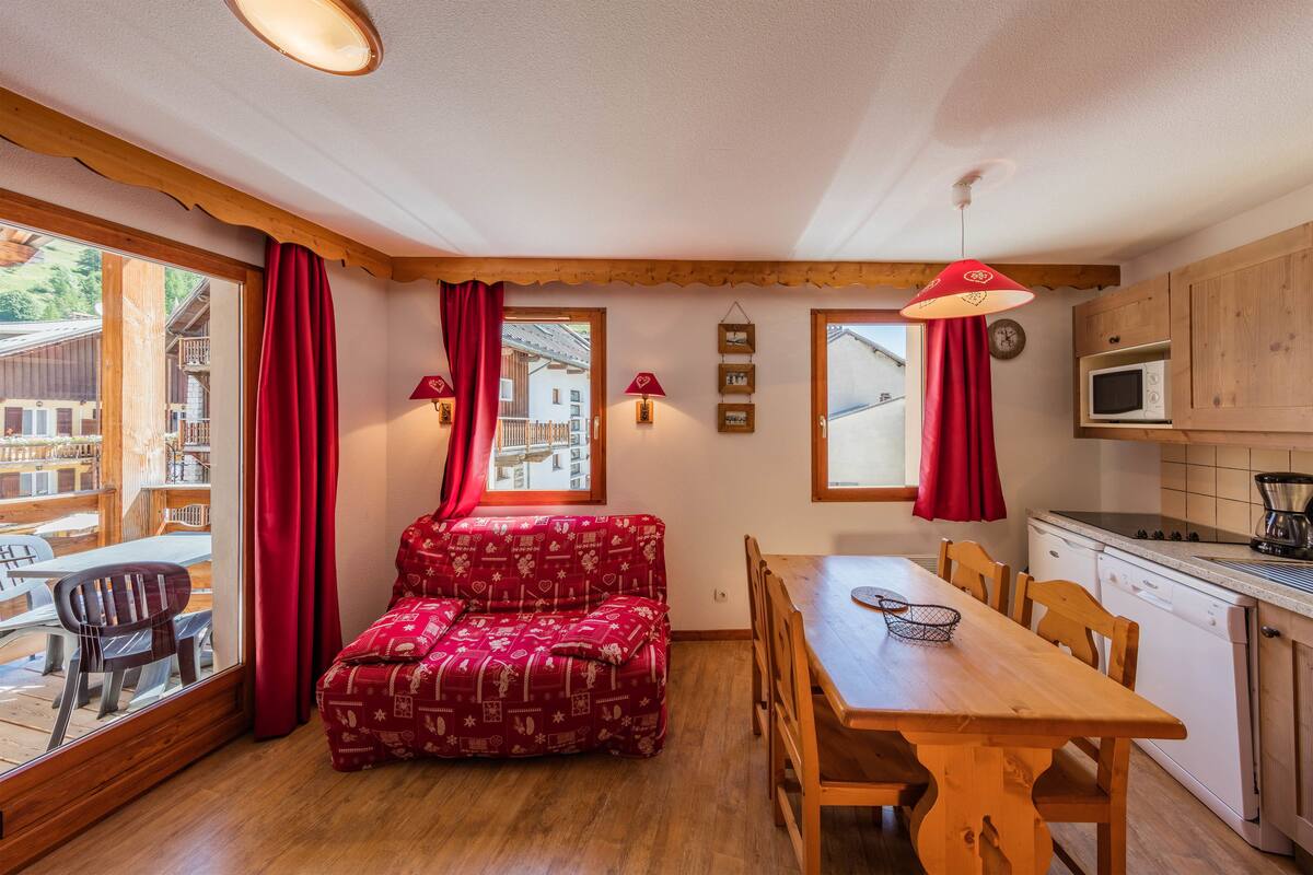 Una habitación acogedora con una mesa de comedor de madera, cortinas rojas y un sofá rojo estampado.