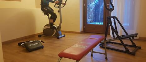Ein Heimfitnessraum mit einem Ergometer, einer Bank und einem Laufband.