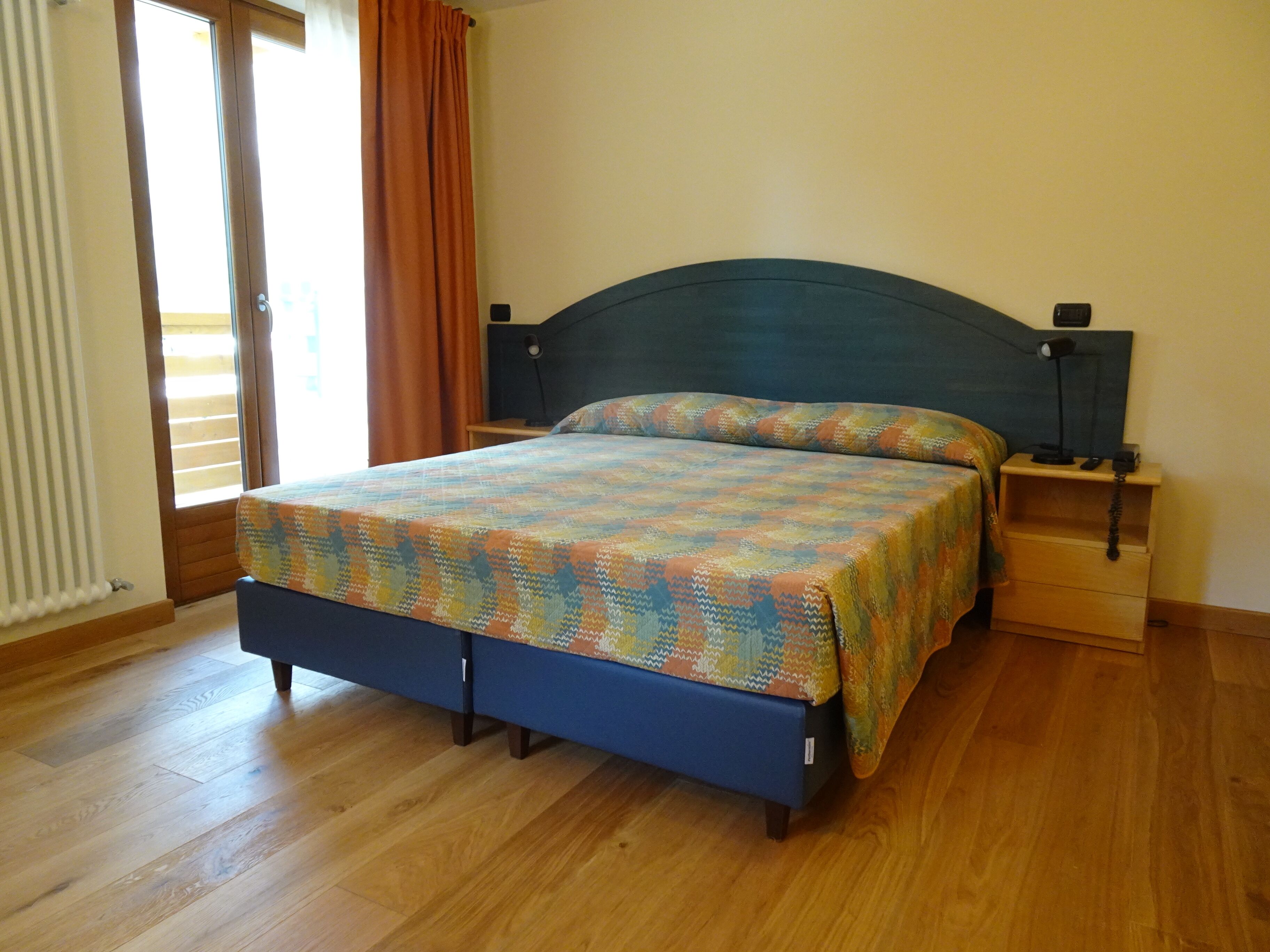 Une chambre à coucher avec un lit, un plancher en bois et une fenêtre avec des rideaux.