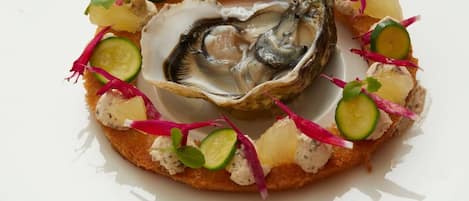A plate with a seafood dish, including an oyster and garnishes.