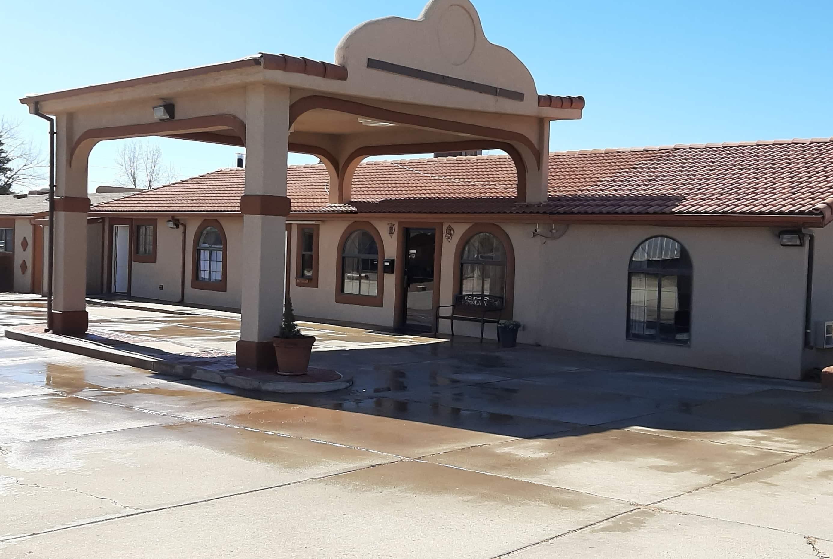 A building with a covered patio area, arched windows, and a tiled roof.