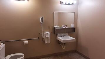 Une salle de bain équipée d’un WC, d’un sèche-mains, d’un porte-serviettes, d’un lavabo, d’un miroir et d’un distributeur de serviettes.