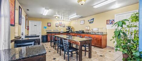 A kitchen with a central island, bar stools, and a dining table.