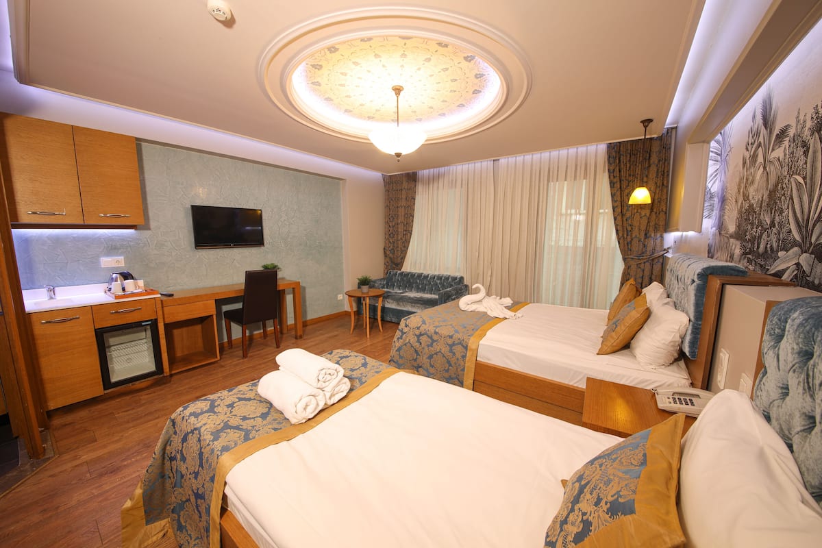 Een hotelkamer met twee bedden, een bureau, een televisie en een zithoek.