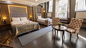 A hotel room with a large bed, a smaller bed, a chair, a table with a plant, and a view of the city through large windows. - Cumbali Luxury Boutique Hotel (Istanbul)