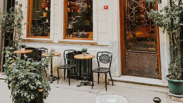 A building with a sign reading "Cumbalh hotel" and a large ornate door. There are outdoor tables and chairs, and potted plants around. - Cumbali Luxury Boutique Hotel (Istanbul)