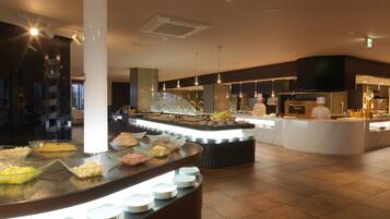 A buffet area with various food items and a chef preparing food in the background.