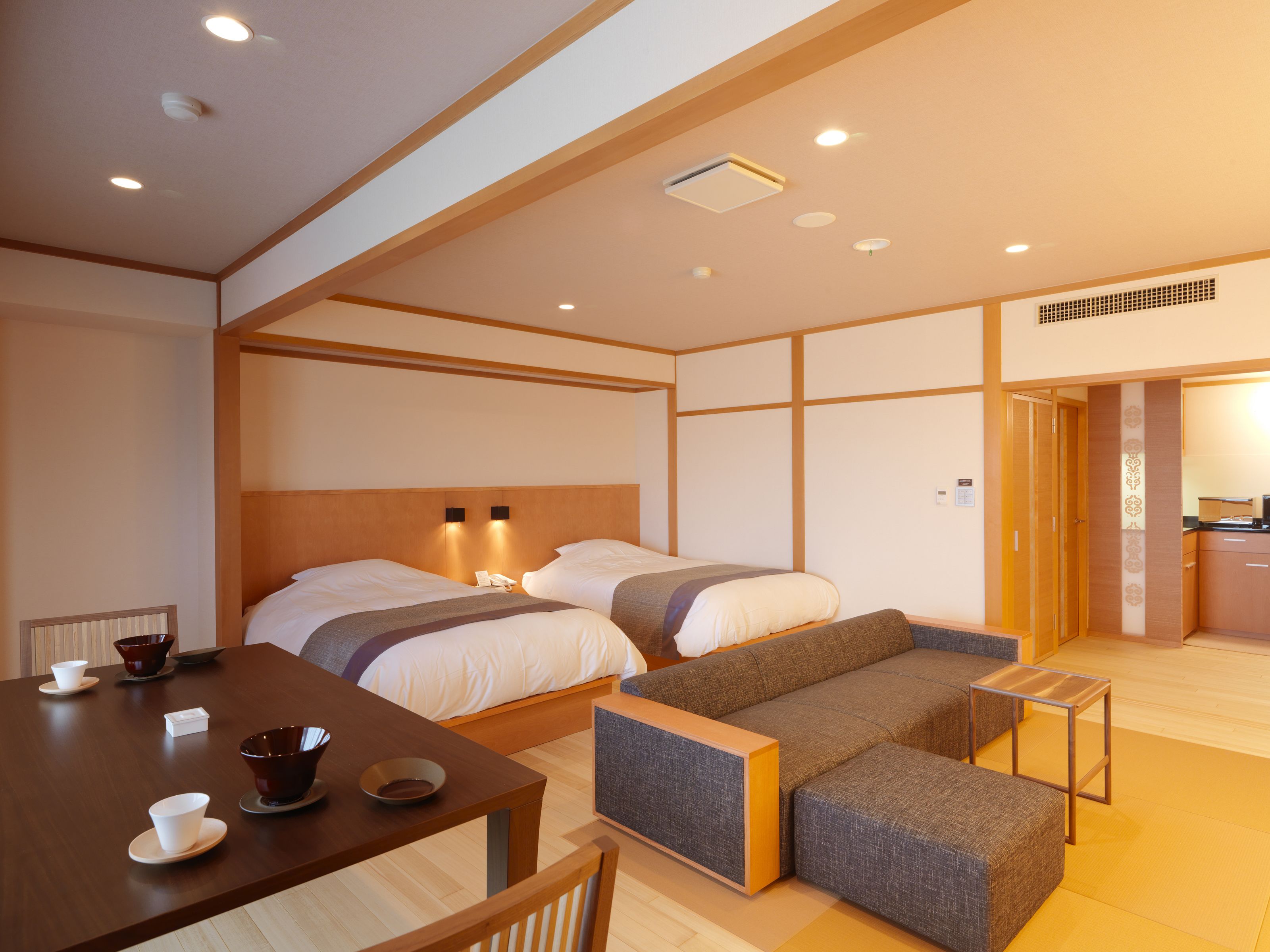 A hotel room with two beds, a dining table with tea sets, and a small sofa.