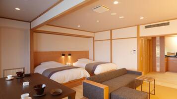 A hotel room with two beds, a dining table with tea sets, and a small sofa.