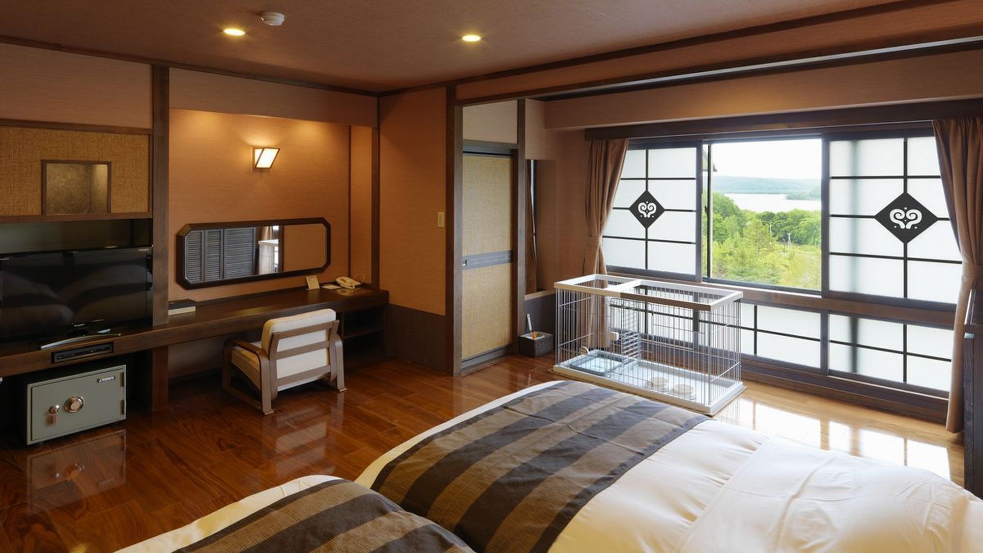 Ein Hotelzimmer mit einem Bett, einem Schreibtisch mit Stuhl, einem Fernseher, einem Safe und einem Fenster mit Blick.