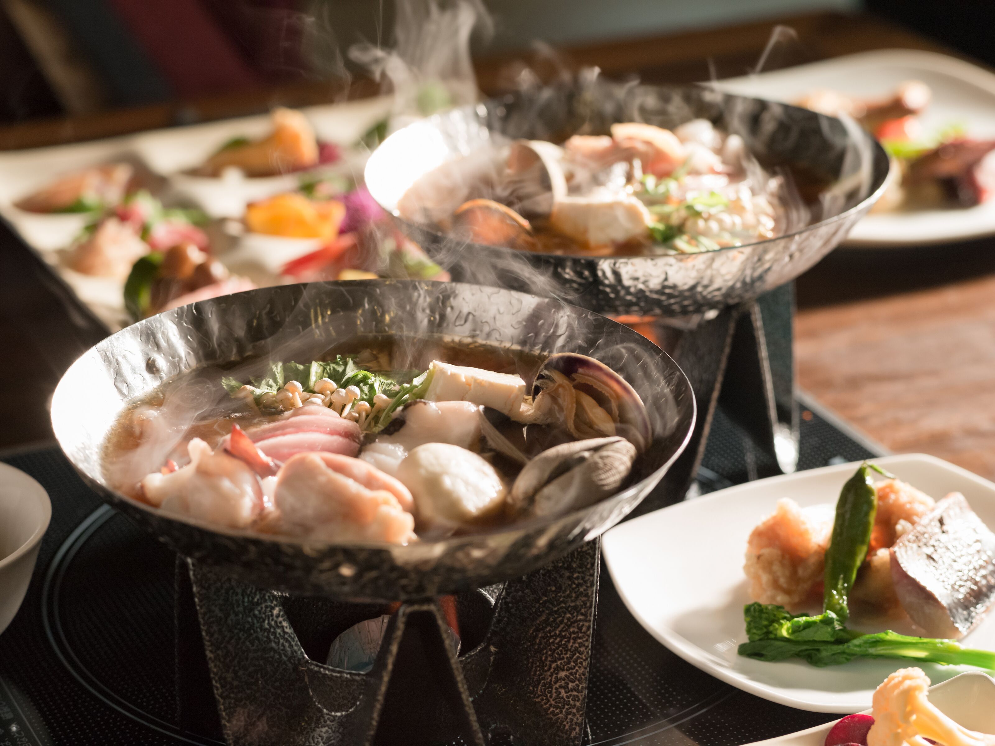 Une table à manger avec plusieurs récipients pour plats mijotés contenant divers fruits de mer et légumes.