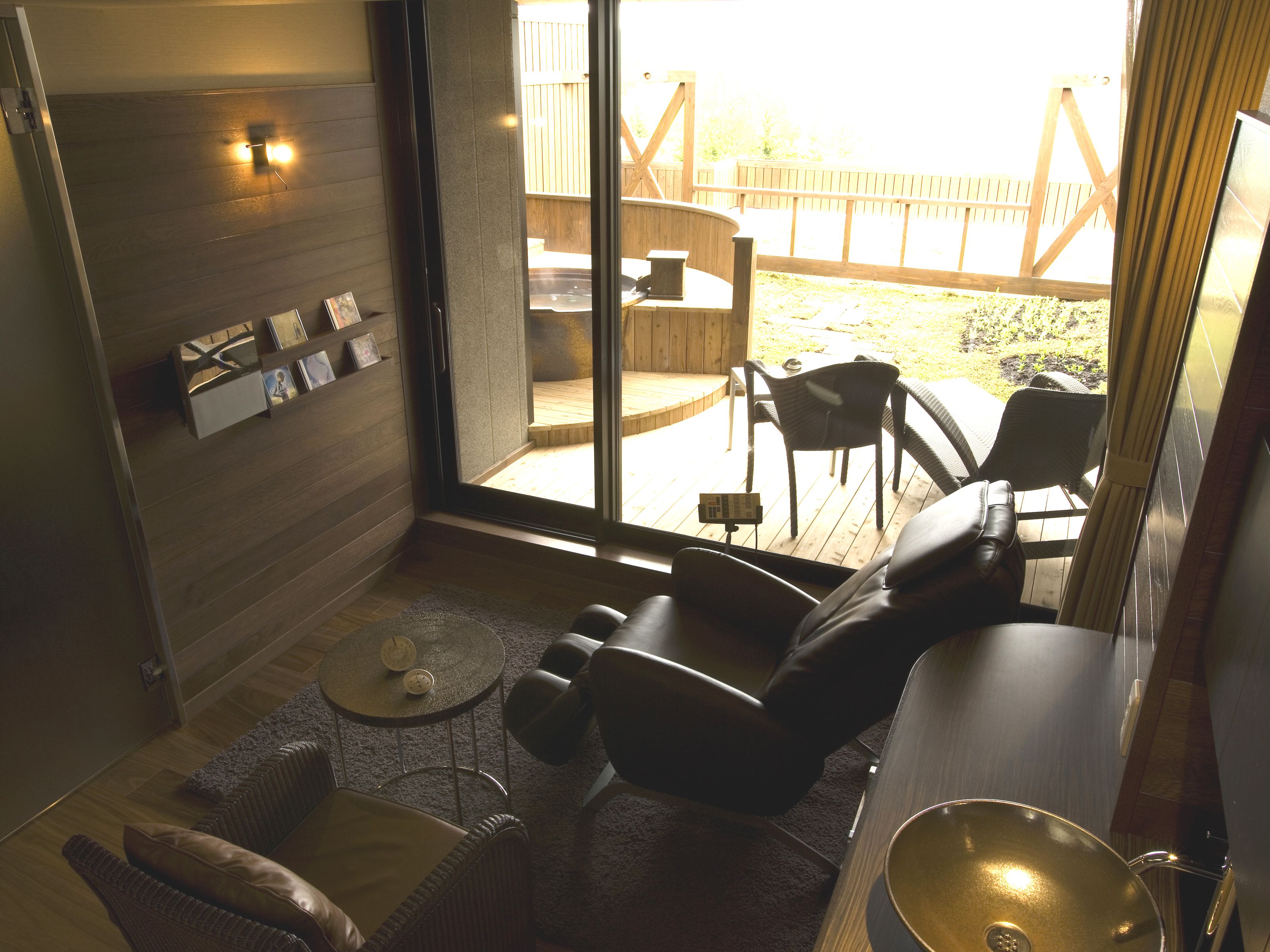 Een modern interieur met een bank, stoelen, een klein tafeltje en uitzicht op het buitendek.