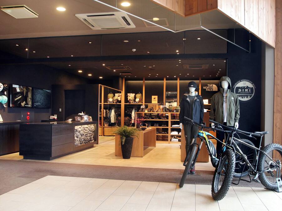Una tienda moderna con zona de recepción, estanterías llenas de zapatos y una bicicleta en primer plano.