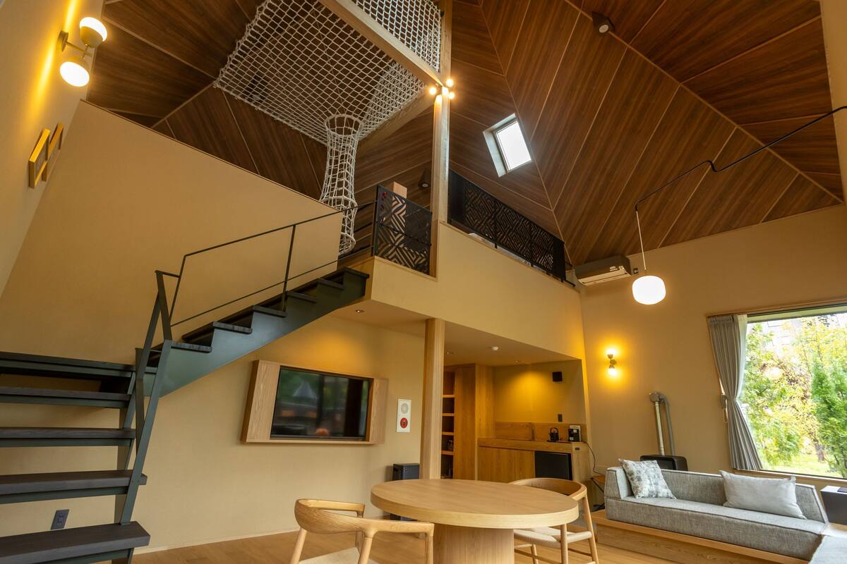 Un interior moderno con una escalera que conduce a un altillo, una zona de comedor y una cocina.