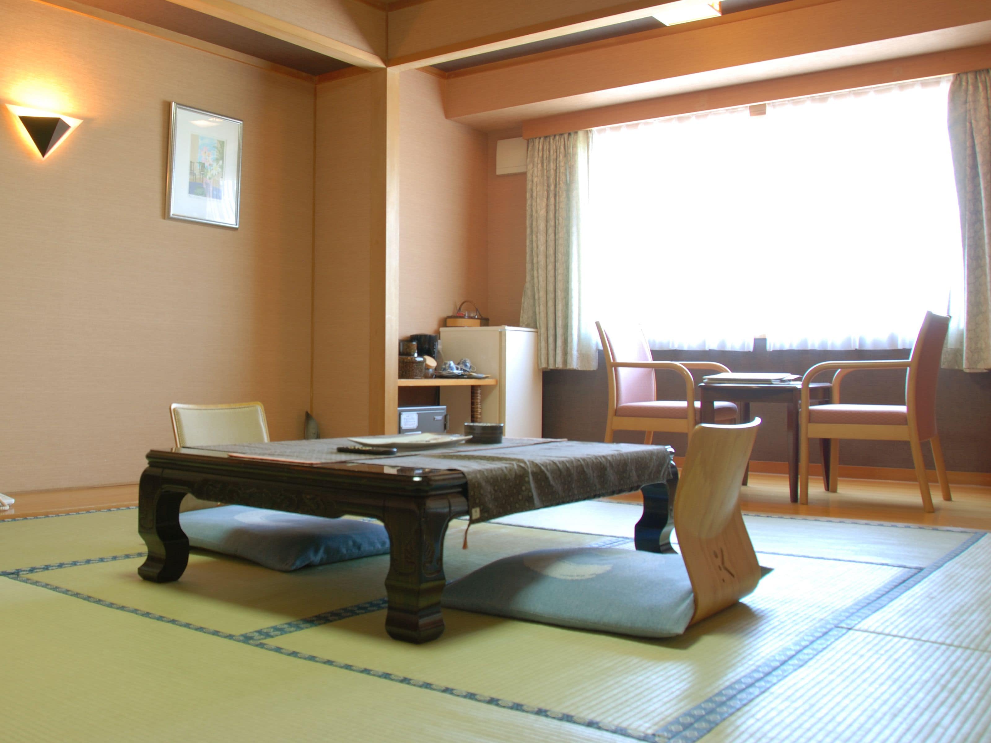 A traditional Japanese room with tatami flooring, a low table, and chairs.